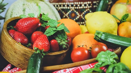 
fruits and vegetables with a bowl with strawberries in the foreground