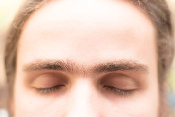 Close up fused eyebrows of a young man of European appearance. The grooming on the face. Men's...