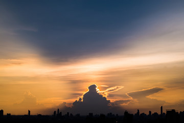 Naklejka premium Silhouette cityscape and many buildings towers with beautiful sunset with twilight sky and cloud. sunset and light rays from clouds shining to sky. Heaven in nature.