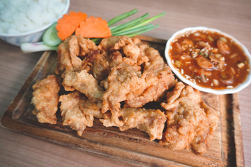 traditional Thai culture fried pork cuisine style or moo tod one of the most favorite famous street fast foods menu at thailand homemade
with hot spicy sauces on table wood dish sticky rice vegetable