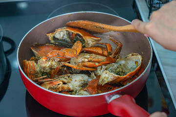 Human hand using spatula and cooking stir-fried crab 