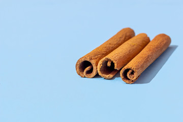 Three cinnamon sticks on a blue background