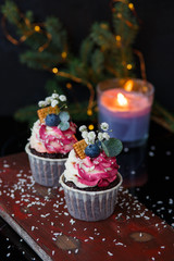 Chocolate cupcakes with mascarpone cream and blueberries on a dark background with candle.