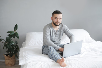 Man in bed works from home. Remote work concept.