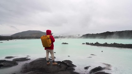 Young traveling man standing/going and looking blue lagoon in Iceland.