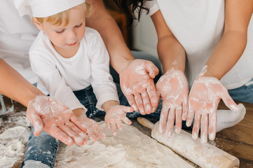 Top view of the two hands of a little boy and parents mom and dad who are preparing knead the...