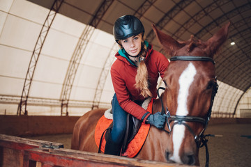 Pretty young woman riding a horse in the arena for equestrian sport