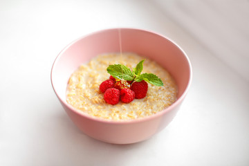 Healthy homemade oatmeal porridge with berries for breakfast in ceramic bowl on a white background.