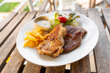 Meat plate of steaks and fries. Chicken and meat on a plate with potatoes in a summer cafe.