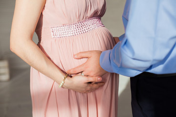 In expecting. Happy pregnant pair in fashion clothes posing in studio