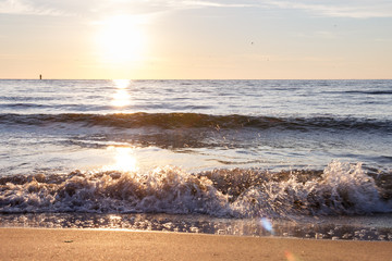 Sunset by the sea. Wave on sea. Beach scene in summertime. Evening on the coast. Sand and water. Silence sunrise. Pacified mood.  Summertime morning. Nobody. Water spray in sunny day. Seascape.