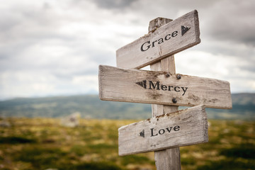 grace mercy love text engraved on old wooden signpost outdoors in nature. Quotes, words and illustration concept