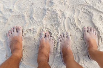 Couple feet standing on white sand beach