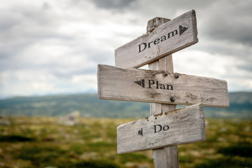dream plan do text engraved on old wooden signpost outdoors in nature. Quotes, words and illustration concept.