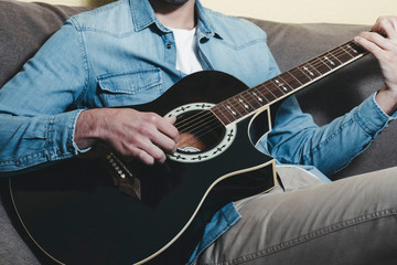 Obraz premium Man playing an black acoustic guitar