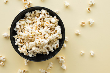 Plate with cheese popcorn, popcorn on a yellow background, top view