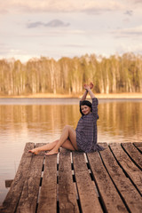 young girl sits on a pier in a summer dress