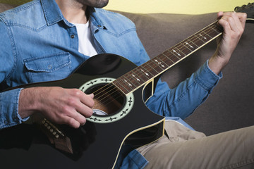 Fototapeta na wymiar Man playing an black acoustic guitar