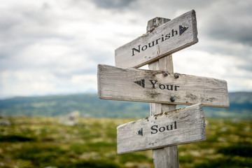 nourish your soul text engraved on old wooden signpost outdoors in nature. Quotes, words and...