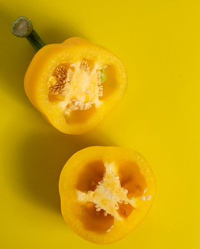 Two Halves Of Yellow Pepper Cut On A Yellow Background Top View