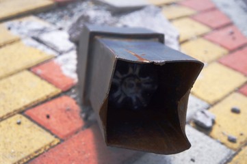 Acera de ladrillos, con elemento oxidado de metal, doblado y aplastado, fotografía industrial,...