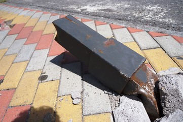 Acera de ladrillos, con elemento oxidado de metal, doblado y aplastado, fotografía industrial,...
