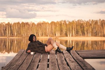 young girl with short hair sits on a pier in the summer