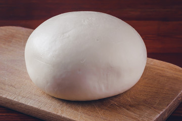 Soft cheese Suluguni on plate on wooden table