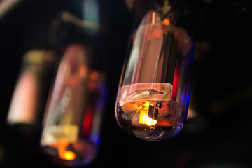 Electrical light buld with purple, yellow, orange light and wire inside on black background. Electron tube. Radio tube. Radio valve. Electric vacuum device isolated on black background. lighting bulb.