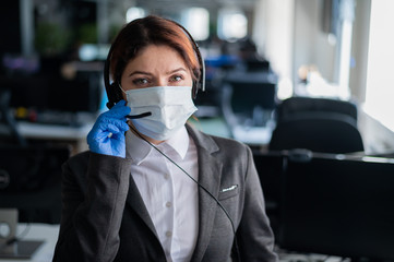 Female call center operator talking to a customer. Woman in mask and gloves at the workplace in the...