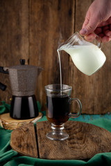 Pour milk into coffee. Make coffee with cream. Glass head in hand. A glass of cappuccino. Geyser...