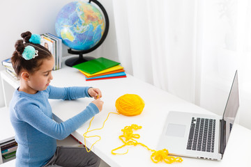 Girl knitting at home on a laptop online, distance learning