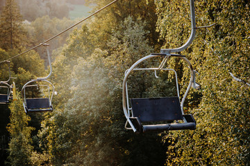 Chairlift in the mountain forest. Beautiful panorama view at sunny summer evening.