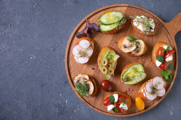 Set different sandwiches with bruschetta and different vegetables. vegetarian concept. summer snack. On a wooden platter.