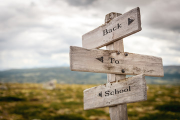 back to school text engraved on old wooden signpost outdoors in nature. Quotes, words and illustration concept.