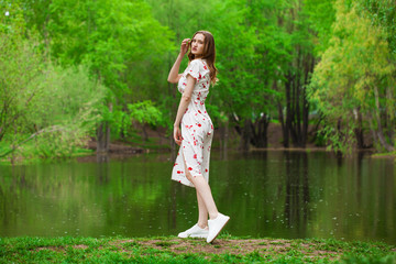 Portrait of a young beautiful woman in white dress posing by the lake
