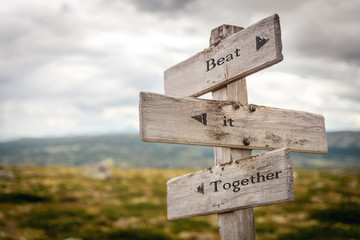 beat it together text engraved on old wooden signpost outdoors in nature. Quotes, words and illustration concept.