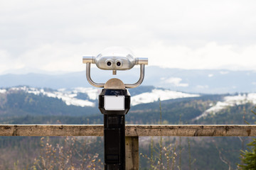 Touristic telescope look on top of mountains, close up metal binoculars on background viewpoint overlooking mountain