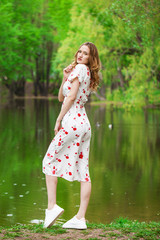 Portrait of a young beautiful woman in white dress posing by the lake