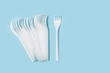Tenedores de plástico blanco desechable sobre fondo celeste liso y aislado. Vista superior. Copy space
