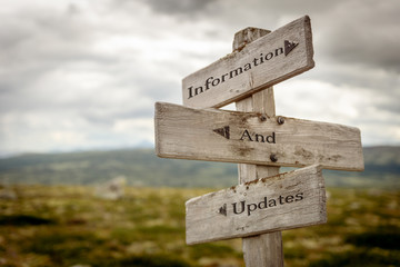information and updates text engraved on old wooden signpost outdoors in nature. Quotes, words and...