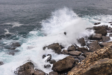 Stormy sea. Wave splash. The wave beats on the shore. Sea spray and foam around the stone. Water element. Storm at sea. Ebbs and flows. Power of nature.