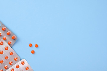 Pills on blue background top view. Orange tablets in the package. Medical pharmacy concept. Health and medicine concept. Copy space