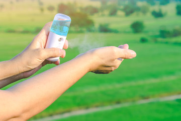 Woman using alcohol nano mist sprayer antiseptic cleaning on her hands protection during Coronavirus pandemic Covid-19.Hand using sanitizer spray.Modern health technology concept.New normal lifestyle.