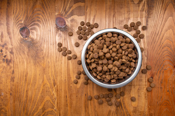 Dog food in bowl on wooden table. Loose dog food. Copy space