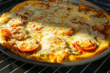 fried homemade pizza in the oven. cook at home. cooking pizza with ingredients cucumbers, tomatoes, cheese, spices sauce, salami pepperoni.