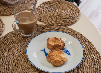 Coffee with milk in a mug and biscuits on a white plate
