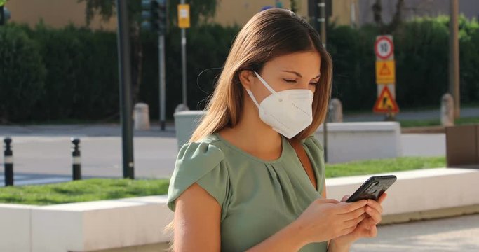 COVID-19 Mobile Application Young Woman Wearing KN95 FFP2 Mask Using Smart Phone App in City Street to Aid Contact Tracing and Self Diagnostic in Response to Coronavirus Disease 2019