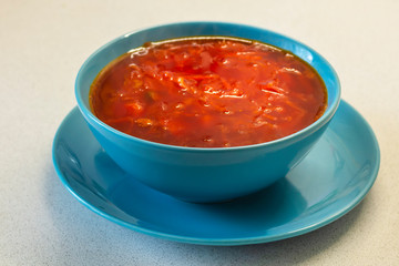 Beetroot soup in a blue plate on a white table. Close-up. Borscht traditional Russian and Ukrainian cuisine.