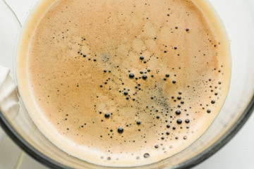 Close-up black coffee espresso in glass cup, top view. Close up shot shows detail of beautiful bubbles on top, selective focus. Full cup of fresh espresso, top view from above. Cup americano with milk
